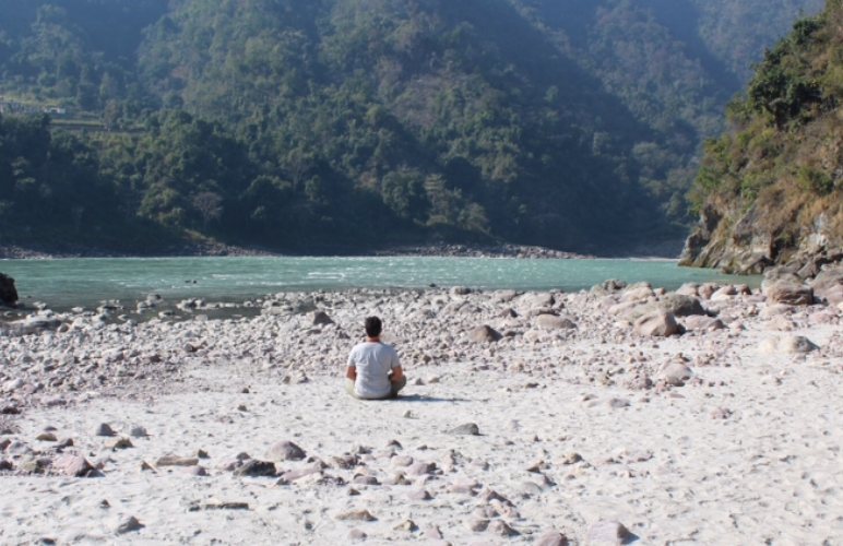 Prof. Daniel De Nardi meditando na margem de um rio, no Himalaia